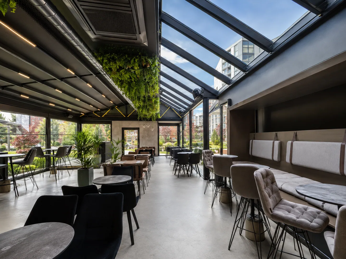 Restaurantbereich unter Glasdach mit Pflanzenwand und Loungebestuhlung