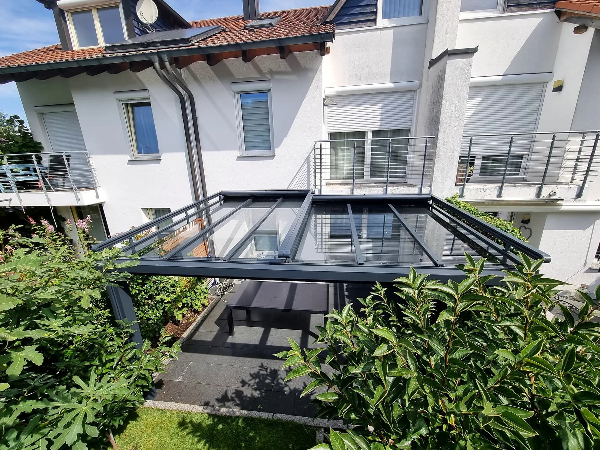 Glasüberdachung eines Balkons mit Blick in den Garten
