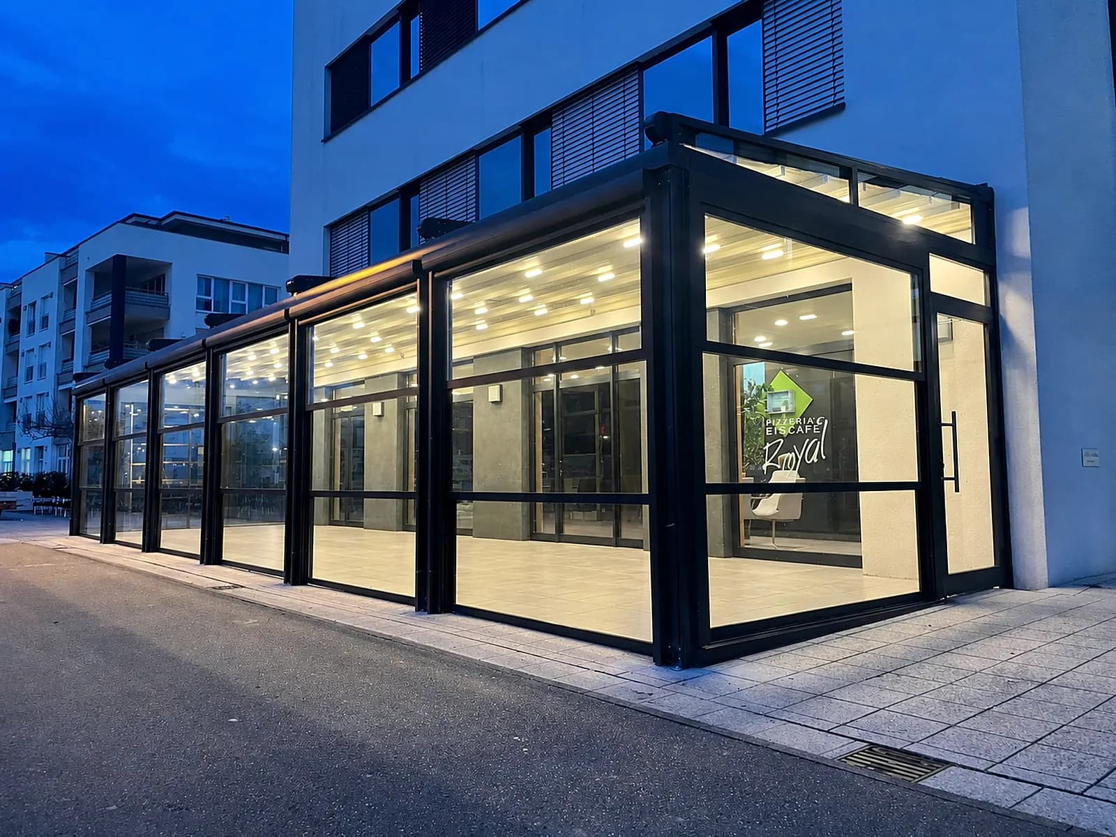 Beleuchtetes Glashaus an einem Gewerbegebäude in der Abenddämmerung
