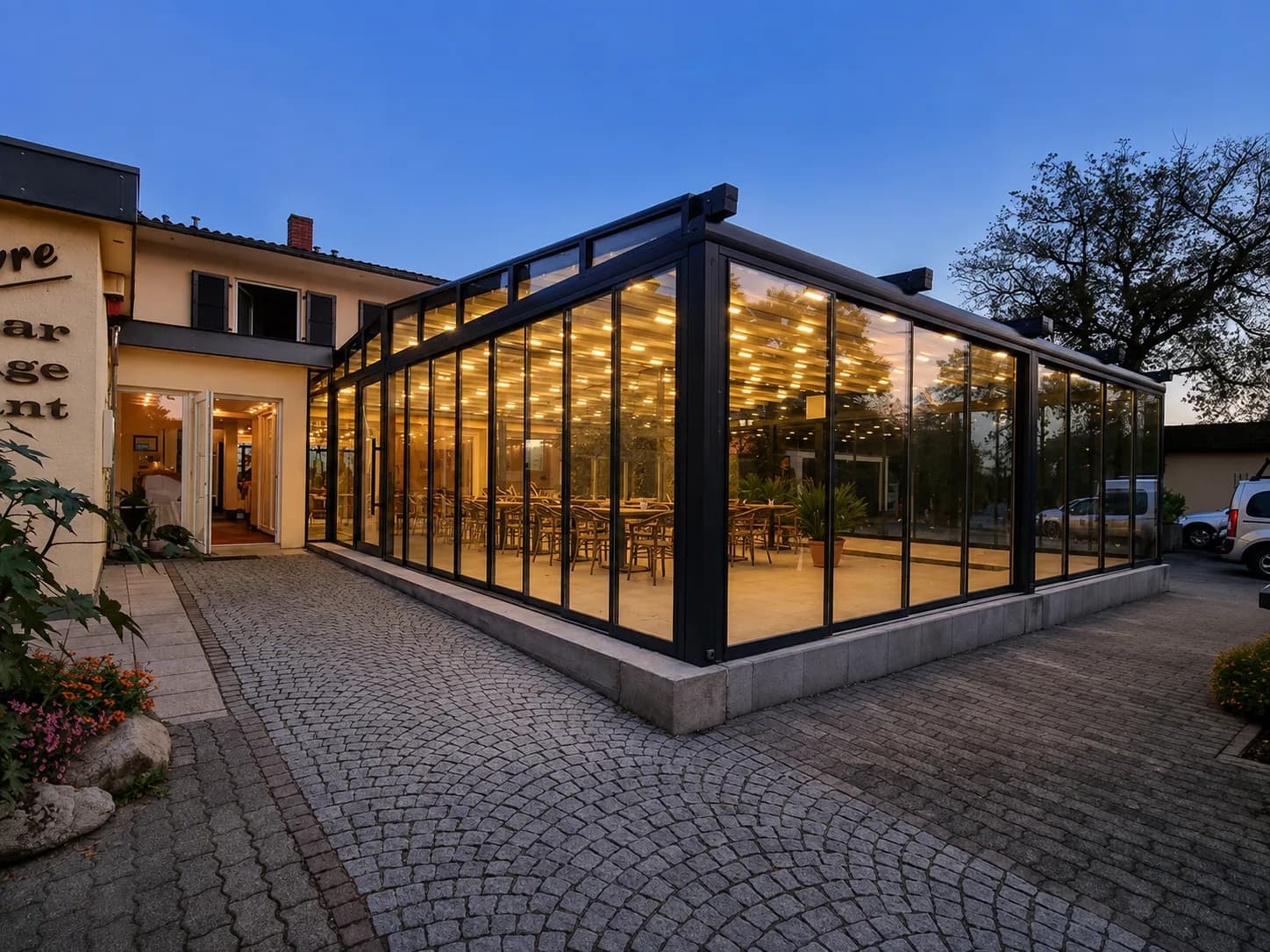 Beleuchtetes Glashaus als Restaurant-Terrasse eines Hotels am Abend