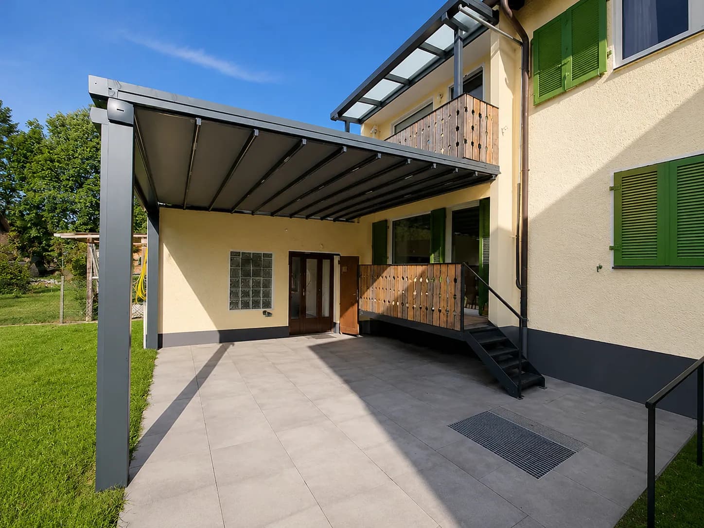 Terrassenüberdachung an einem Haus mit grünen Fensterläden