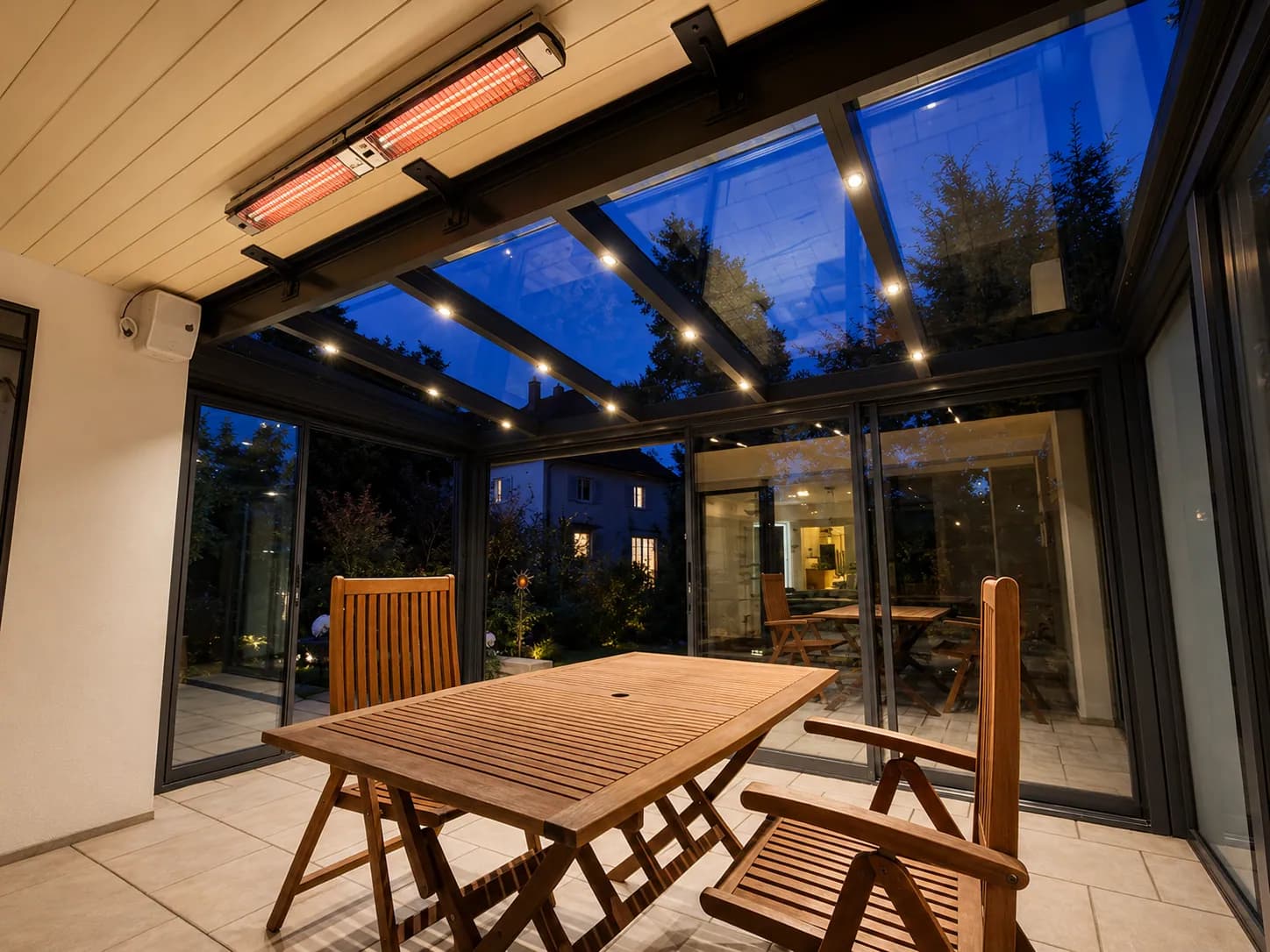Terrassenüberdachung am Abend mit Heizstrahler, LED-Spots und Holzmöbeln