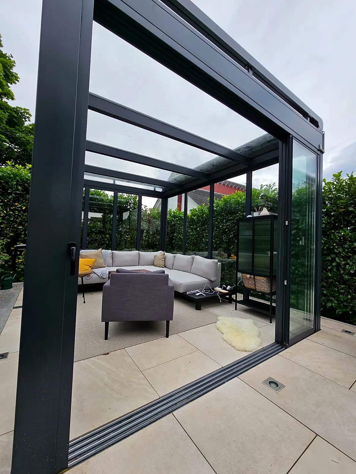 Schiebeverglasung einer Terrassenüberdachung mit Lounge dahinter