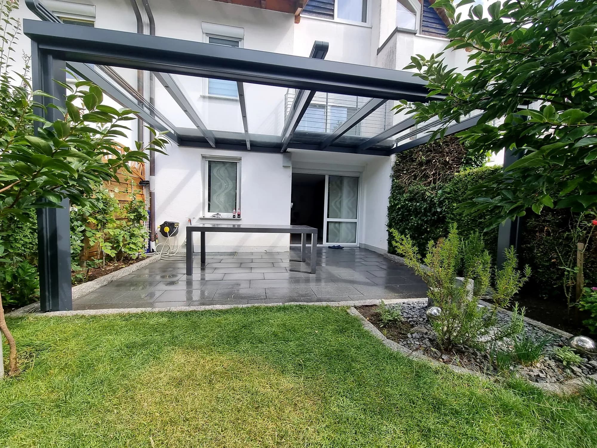 Terrassendach aus Aluminium und Glas an einem Wohnhaus mit Garten