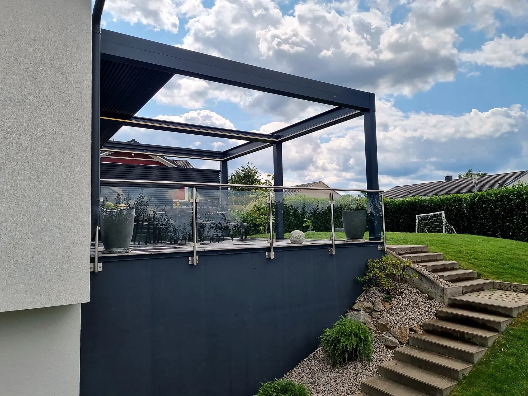 Lamellendach mit Glasgeländer auf einer Terrasse in Hanglage