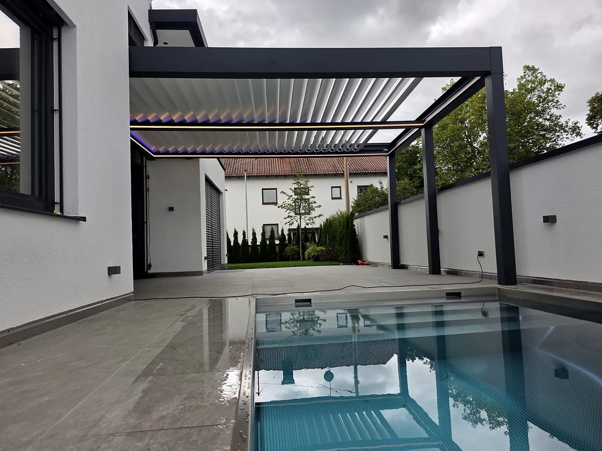 Freistehendes Lamellendach neben dem Pool eines modernen Wohnhauses