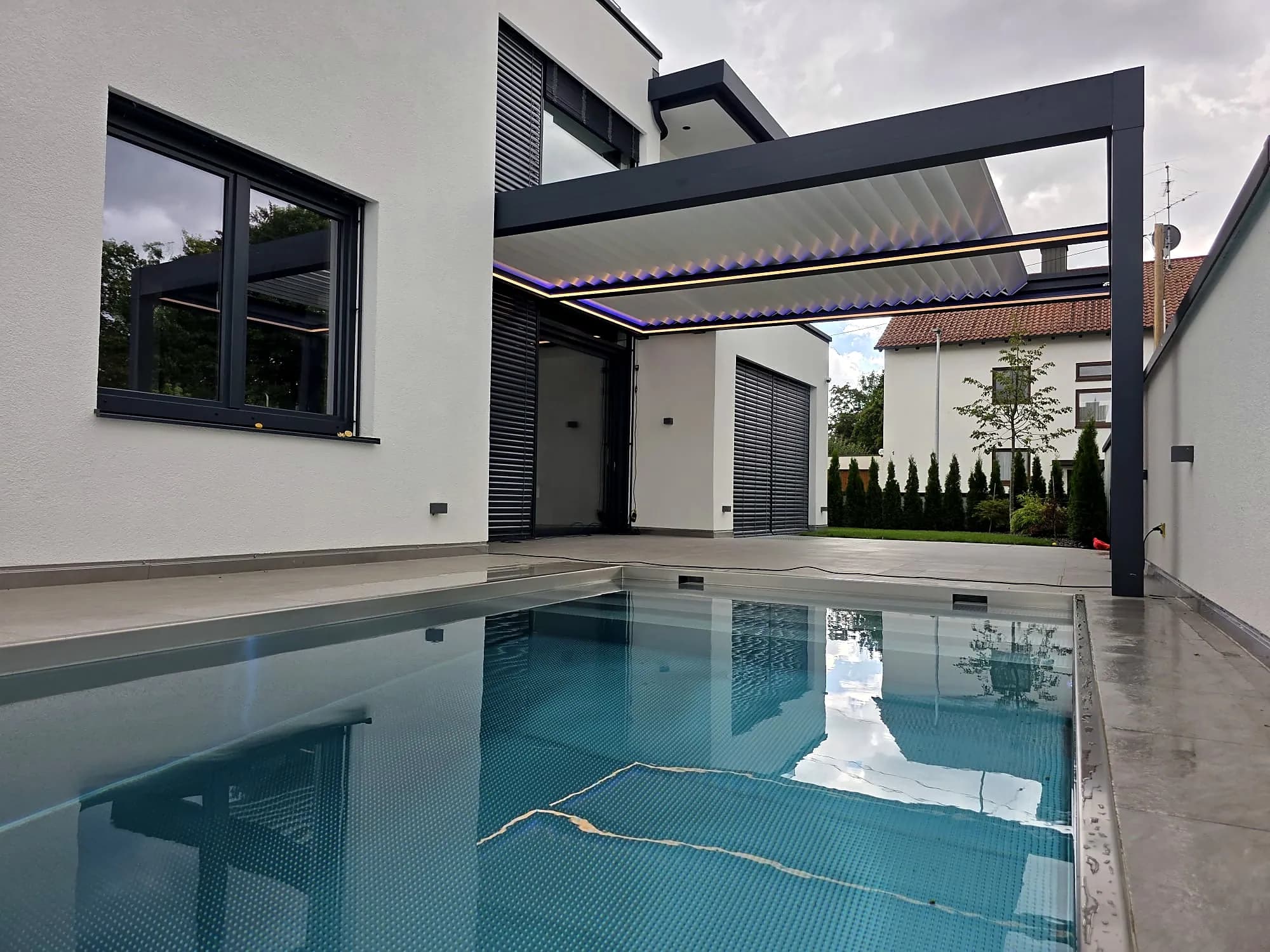 Lamellendach und Pool am Abend mit Blick auf die Terrasse