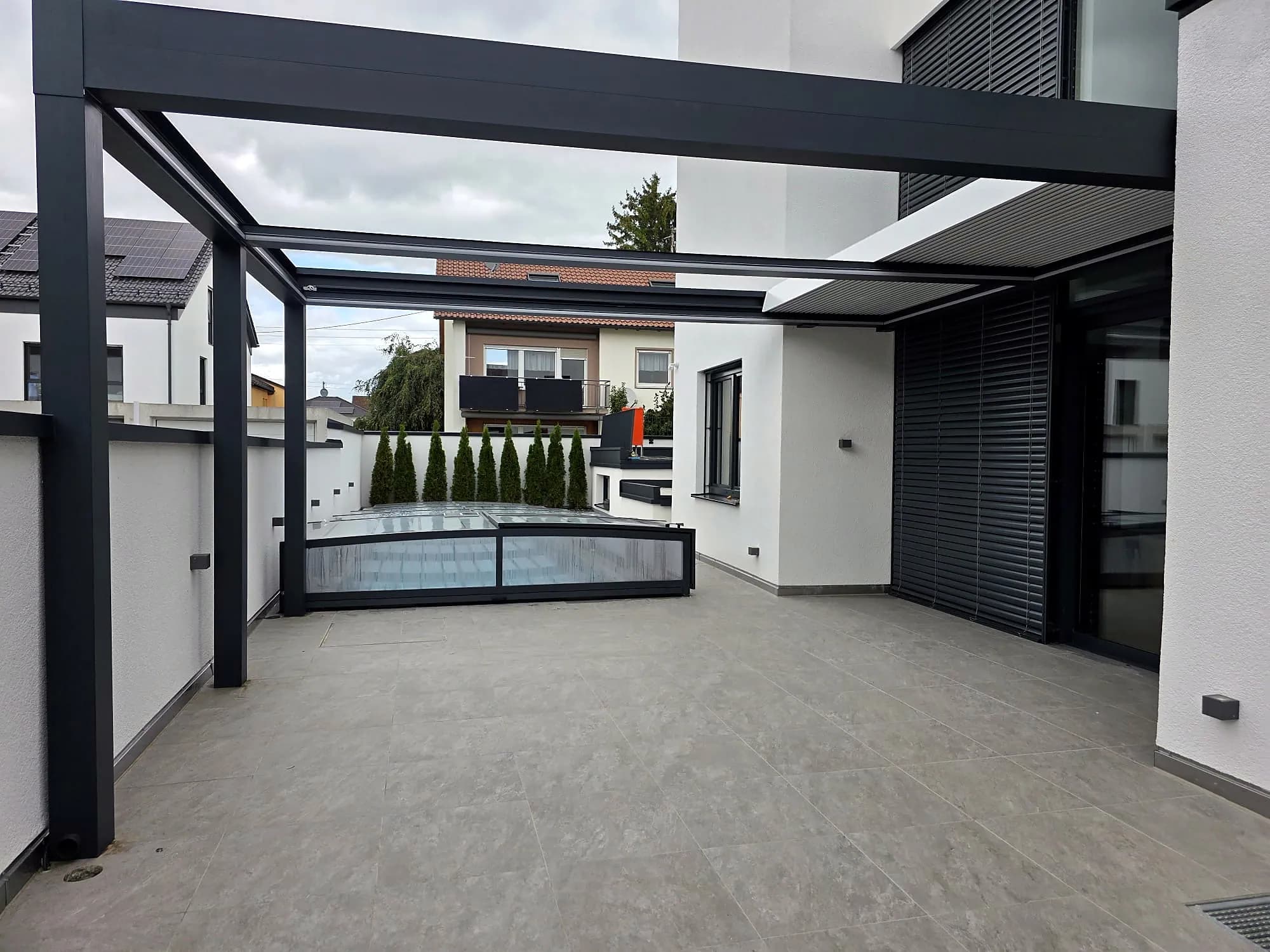 Lamellendach in Anthrazit über der Poolterrasse eines modernen Hauses