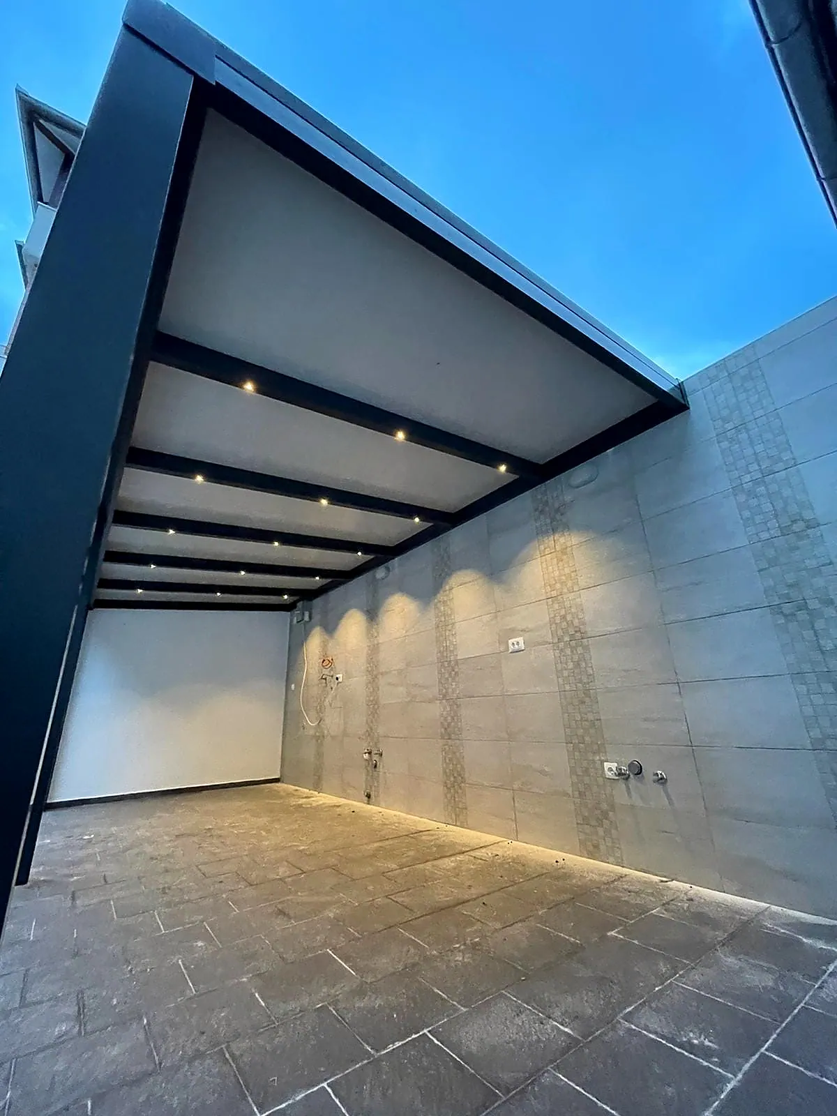 Lamellendach von unten mit integrierten LED-Spots vor blauem Abendhimmel