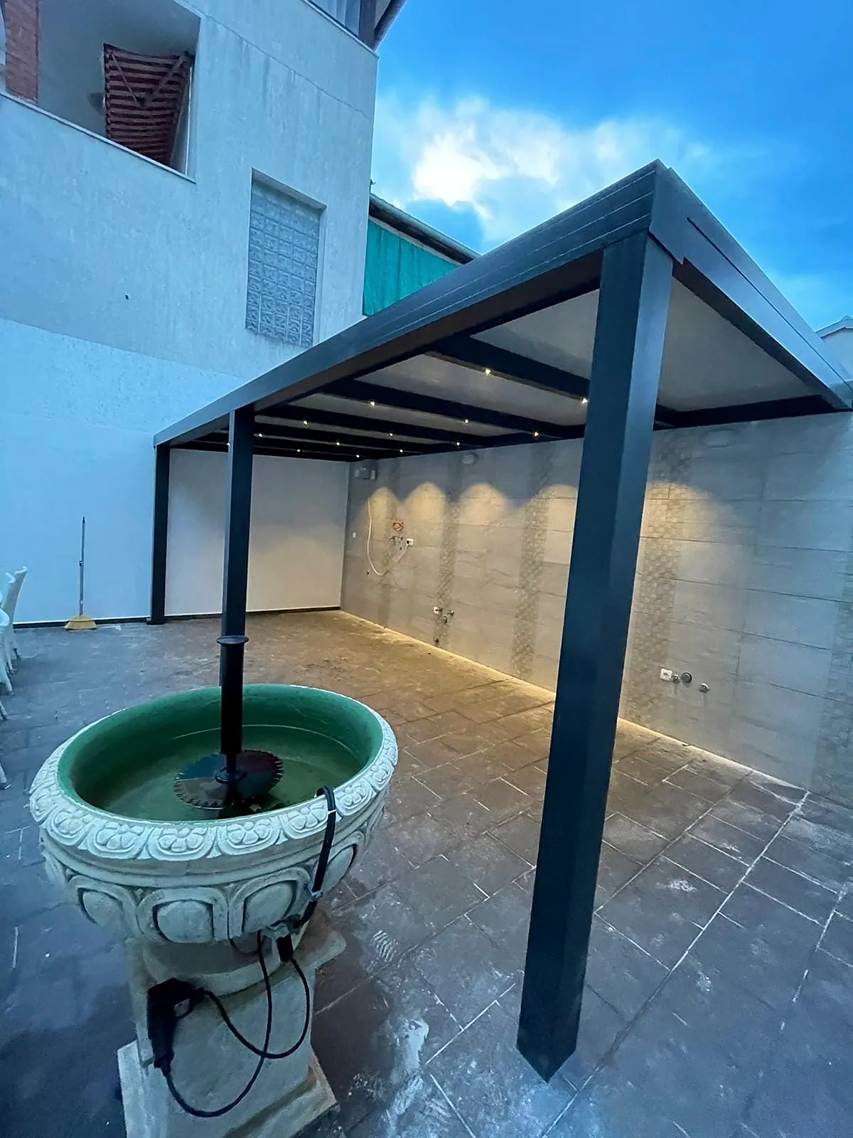 Untersicht eines Lamellendachs mit nassem Terrassenboden