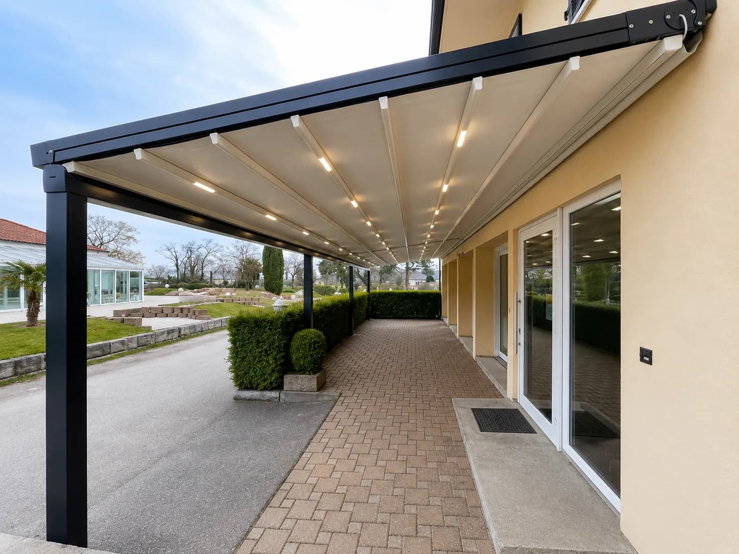 Lange Pergola mit Faltdach und LED-Beleuchtung entlang einer Hausfassade