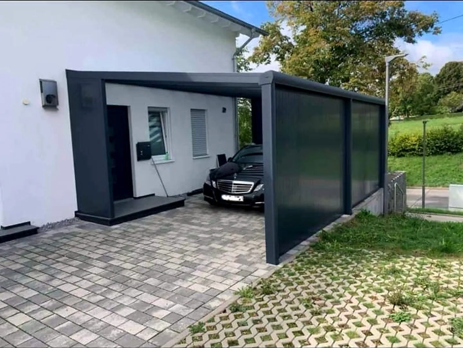 Carport in Anthrazit mit geschlossener Seitenwand vor einer Garage
