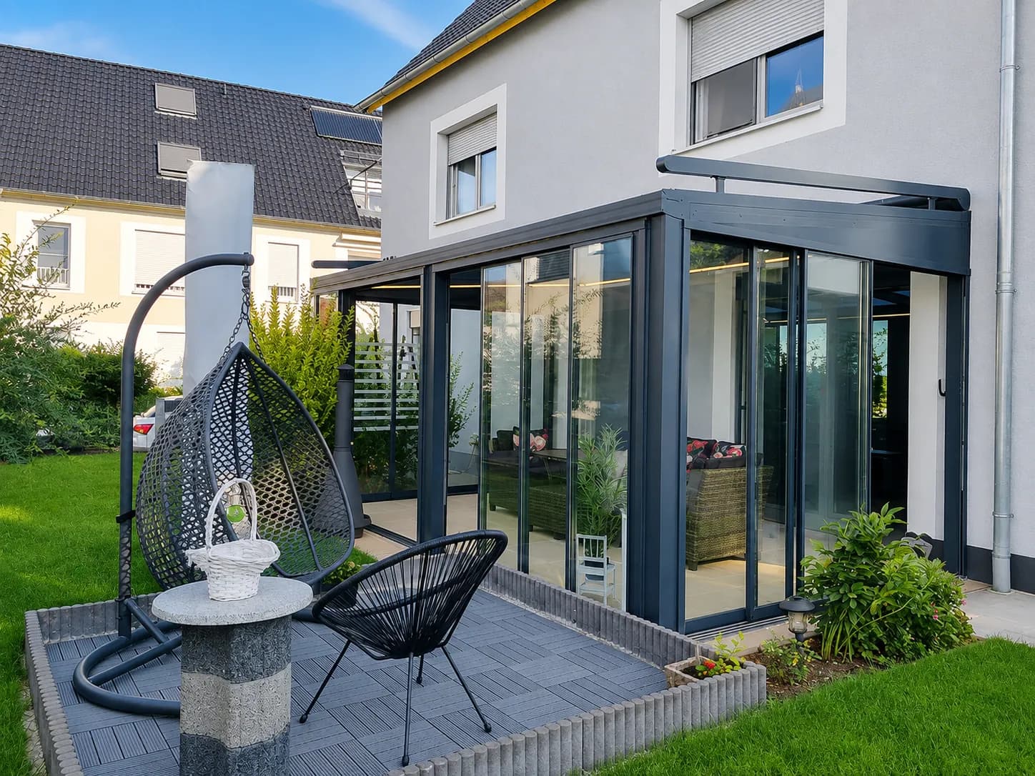 Glashaus am Wohnhaus in der Abendsonne mit Hängesessel auf der Terrasse
