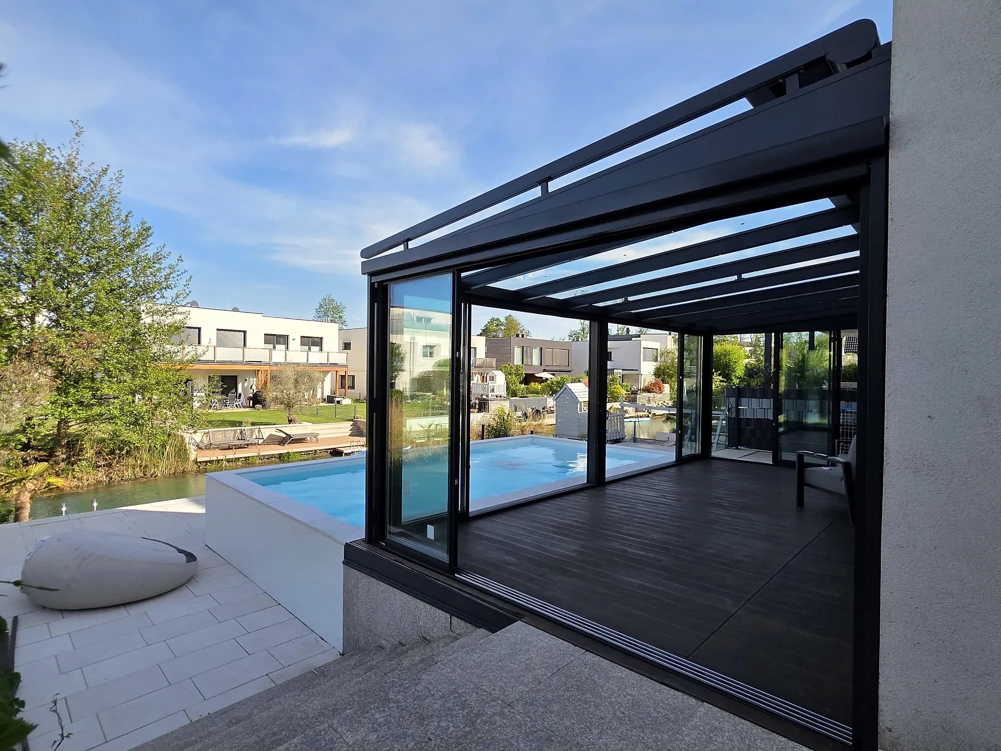 Glasoase mit Schiebeverglasung neben dem Pool eines modernen Hauses