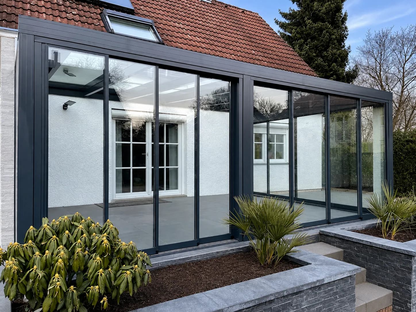 Wintergarten in Anthrazit an einem Wohnhaus mit rotem Ziegeldach