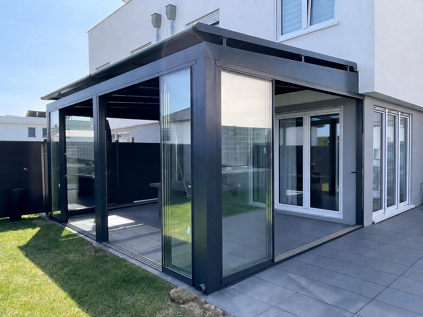Glasanbau in Anthrazit an modernem weißem Wohnhaus mit Terrasse